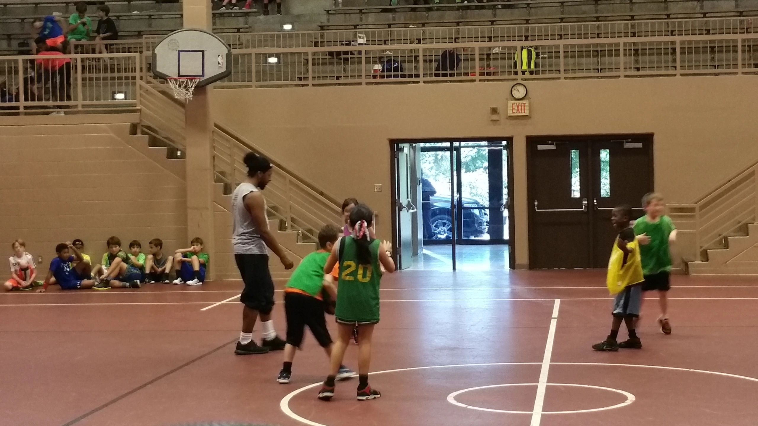 Youth basketball game in gymnasium with green jerseys